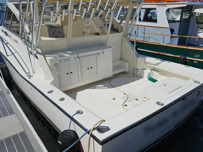 Slide: The Image of 2001 Carolina Classic Express 35 boat docked, featuring spacious deck and fishing rod holders. - 4