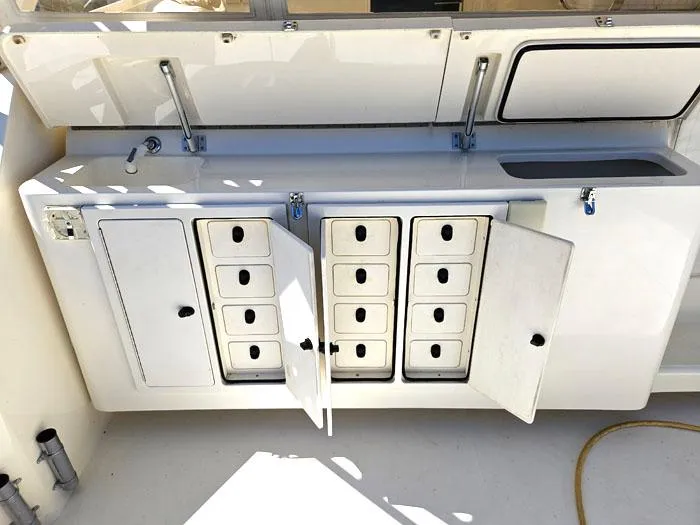 Slide: The Image of 2001 Carolina Classic Express 35 boat storage compartments with open doors and multiple drawers. - 6