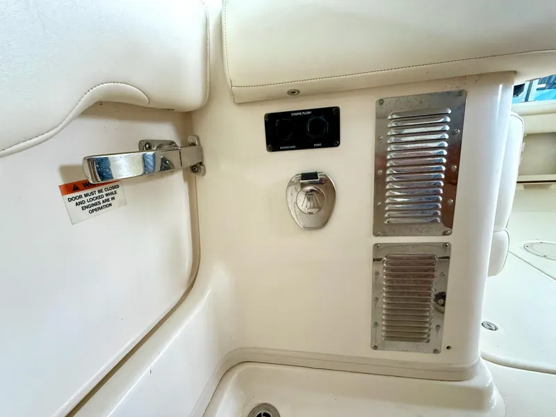 Slide: The Image of Interior view of a 2018 Grady-White Marlin 300 boat, featuring a door latch and engine flush controls. - 20