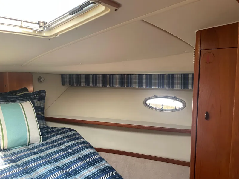 Slide: The Image of Cozy cabin interior of 1998 Tiara Yachts 3500 Open with plaid bedding and porthole window. - 16