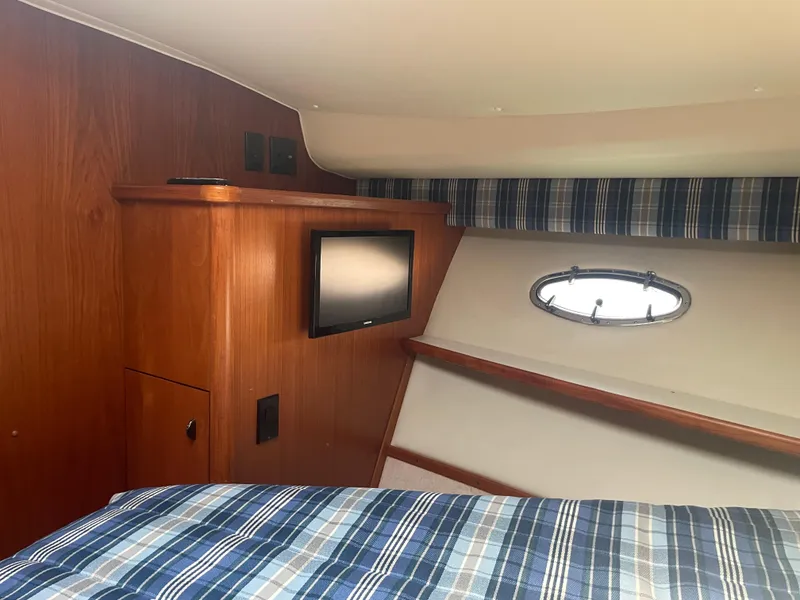 Slide: The Image of 1998 Tiara Yachts 3500 Open cabin interior with wood paneling and plaid bedding. - 18