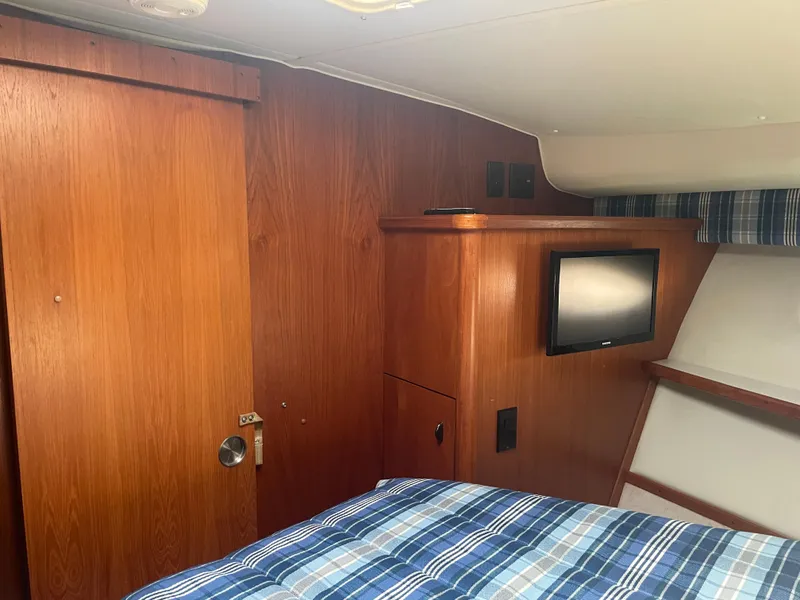 Slide: The Image of Interior of 1998 Tiara Yachts 3500 Open with wood paneling and plaid bedding. - 19
