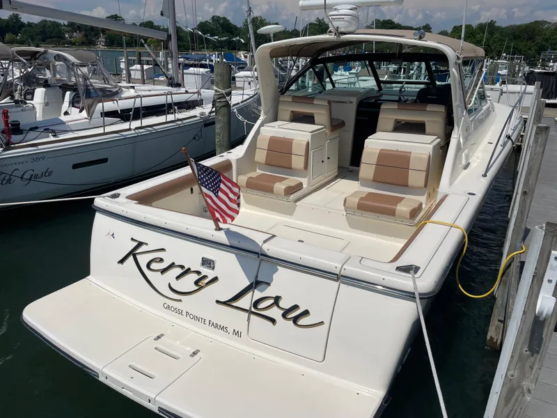 Slide: The Image of 1998 Tiara Yachts 3500 Open docked, featuring spacious seating and American flag. - 3