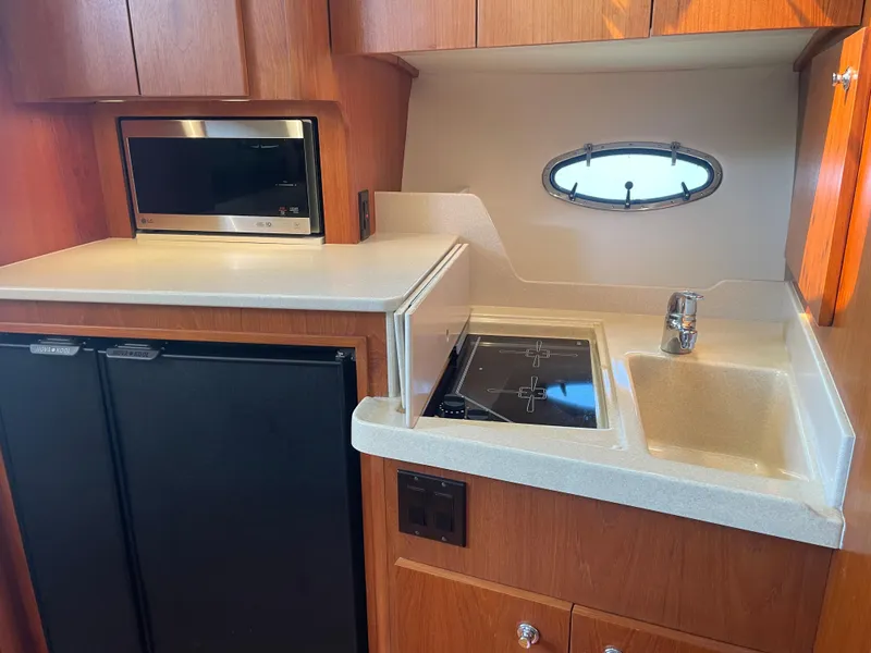 Slide: The Image of 1998 Tiara Yachts 3500 Open galley with microwave, stove, sink, and compact refrigerator. - 31