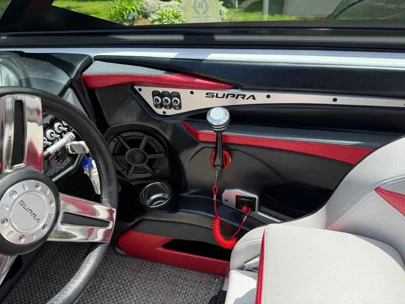 Slide: The Image of Interior of a 2015 Supra SE450-550 boat, featuring steering wheel and dashboard controls. - 13