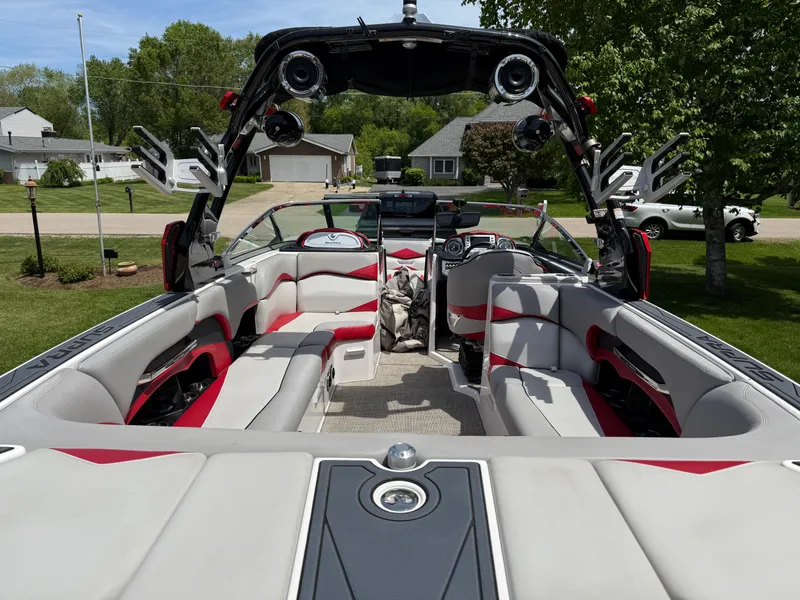 Slide: The Image of 2015 Supra SE450-550 boat interior with red and gray seating, parked in a residential area. - 15