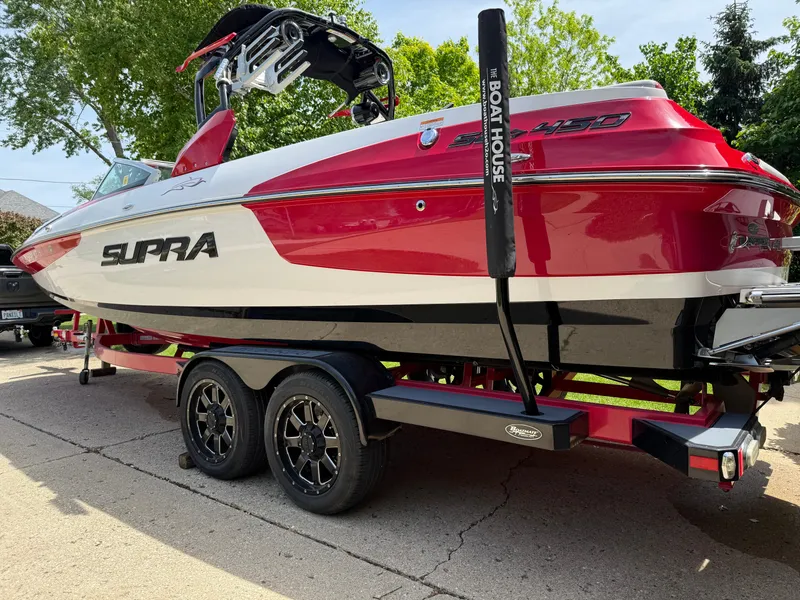 Slide: The Image of Red and white 2015 Supra SE450-550 boat on a trailer, parked outdoors. - 5