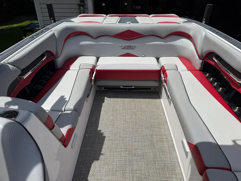Slide: The Image of 2015 Supra SE450-550 boat interior with red and white seating, cup holders, and carpeted floor. - 16