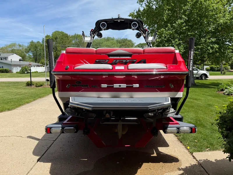 Slide: The Image of Red 2015 Supra SE450-550 boat parked on driveway, surrounded by greenery. - 3