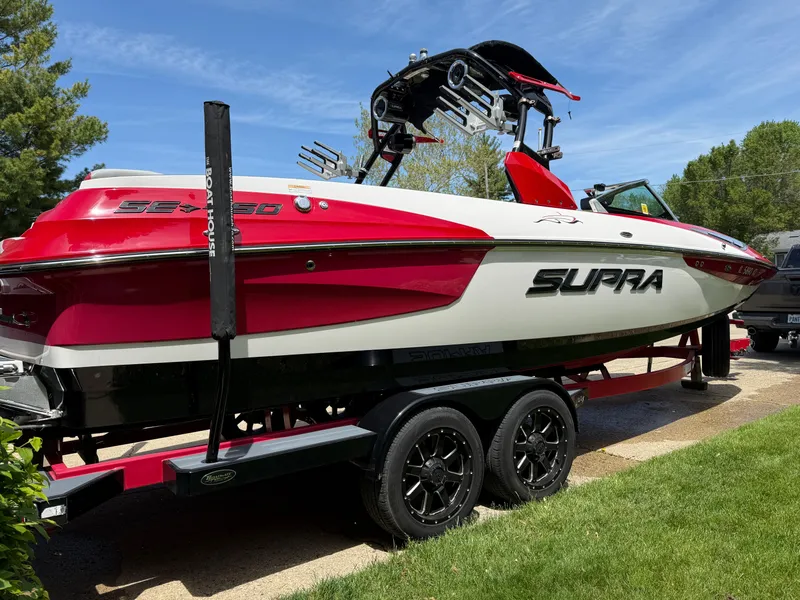 Slide: The Image of 2015 Supra SE450-550 boat on trailer, red and white design, parked on grass. - 8