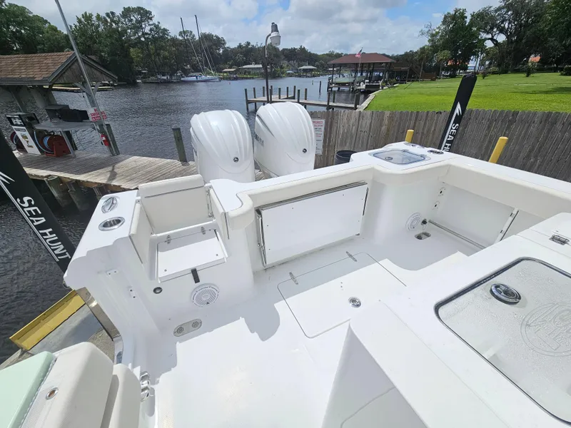 Slide: The Image of 2025 Sea Hunt Gamefish 28 FS boat with dual engines docked by a scenic waterfront. - 13