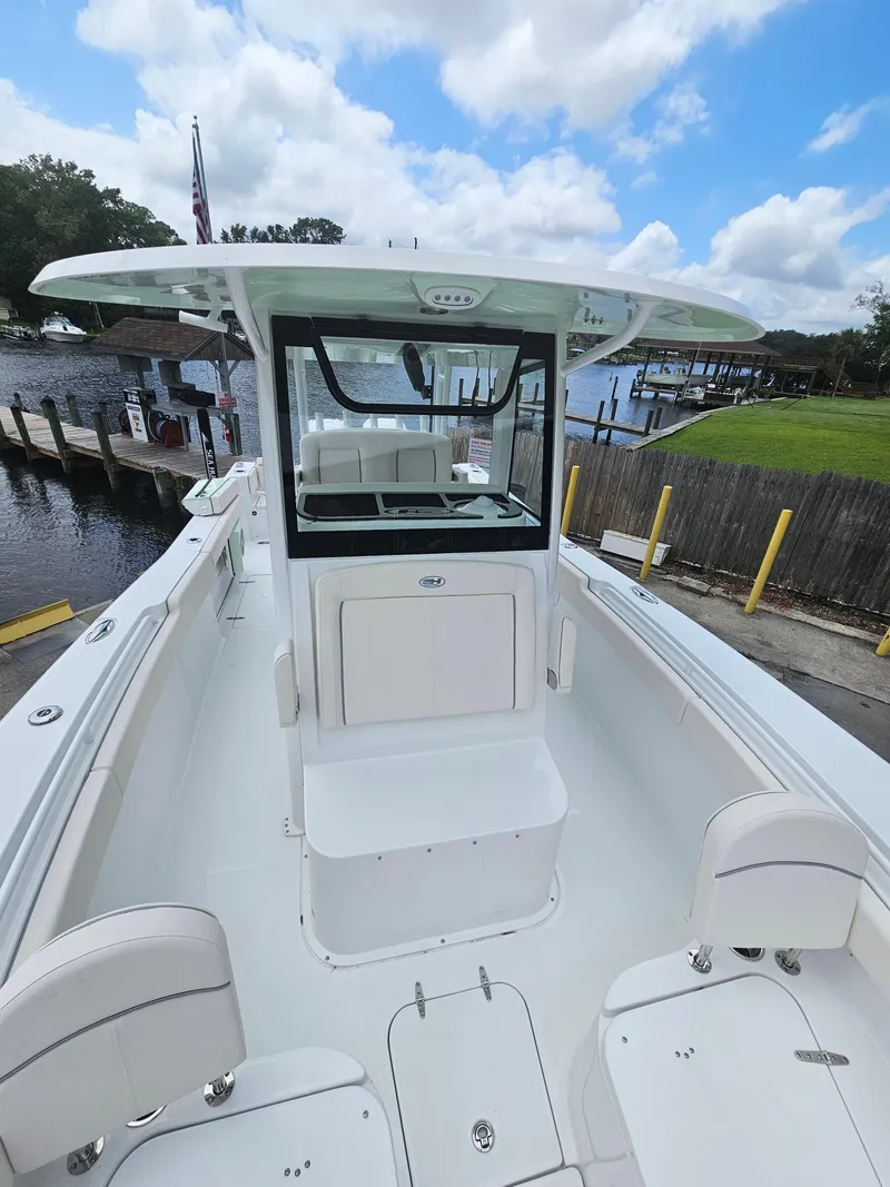 Slide: The Image of 2025 Sea Hunt Gamefish 28 FS boat docked by a scenic waterfront. - 29