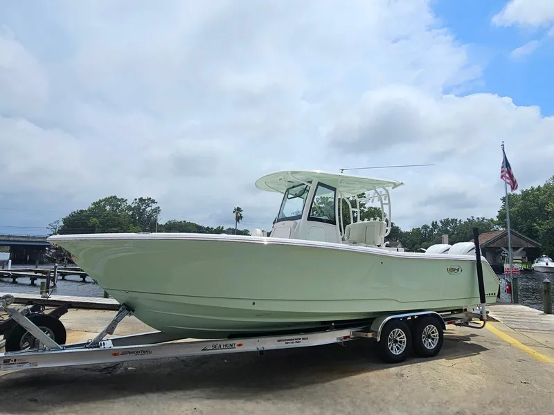 Slide: The Image of 2025 Sea Hunt Gamefish 28 FS boat on trailer, dockside under cloudy sky. - 41