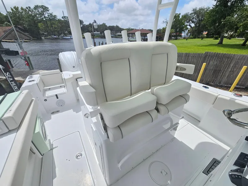Slide: The Image of 2025 Sea Hunt Gamefish 28 FS boat with white cushioned seating, docked by a scenic river. - 12