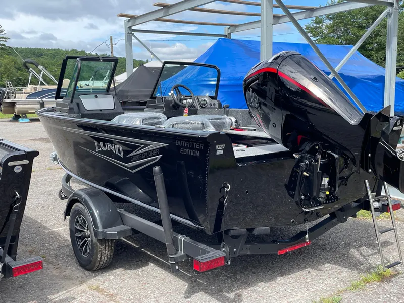 Slide: The Image of 2026 Lund 1800 Explorer Sport boat with outboard motor, parked on a trailer. - 7