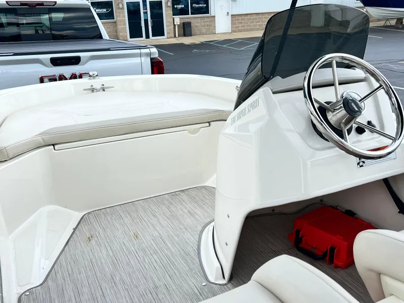 Slide: The Image of 2022 Boston Whaler 130 Super Sport interior with steering wheel and seating, parked near a GMC truck. - 9