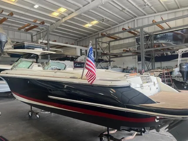 Slide: The Image of 2018 Chris-Craft Launch 27 boat in indoor storage, featuring sleek design and American flag. - 5