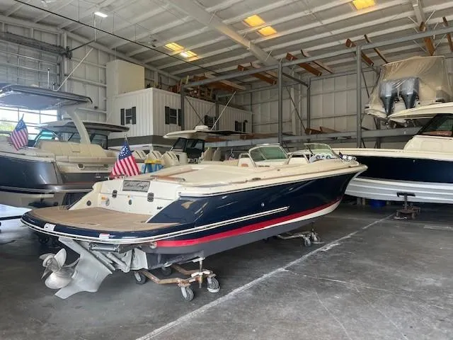 Slide: The Image of 2018 Chris-Craft Launch 27 boat in indoor storage, featuring sleek design and American flag. - 7