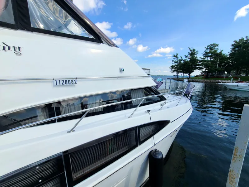 Slide: The Image of 2001 Carver 506 Motor Yacht docked by a serene lake under a blue sky. - 7