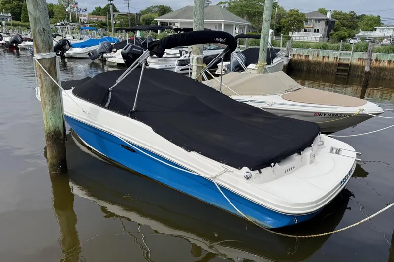 The Image of 2014 Sea Ray 205 Sport boat docked with black cover, blue hull. - 0