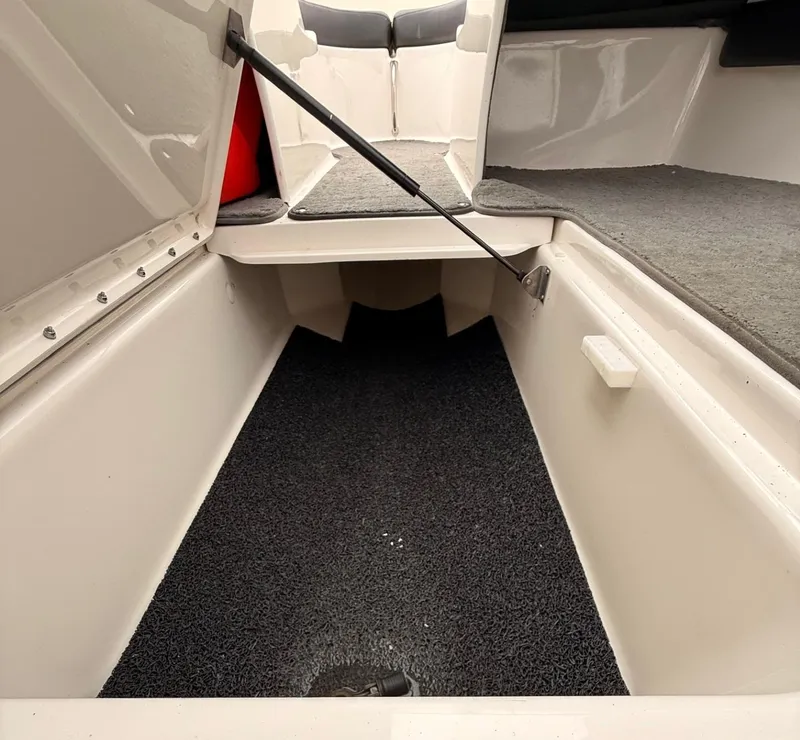 Slide: The Image of Open storage compartment in 2014 Sea Ray 205 Sport boat, featuring carpeted interior. - 10