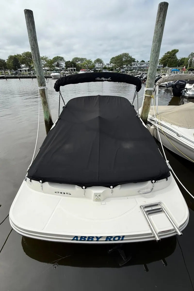 Slide: The Image of 2014 Sea Ray 205 Sport boat docked with black cover in a marina. - 2