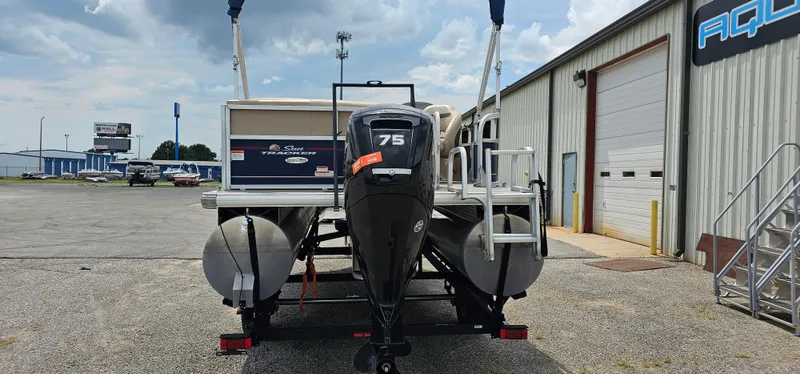 Slide: The Image of 2018 Sun Tracker PB-18 DLX pontoon boat with 75 HP engine, parked outside a warehouse. - 2