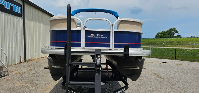 Slide: The Image of 2018 Sun Tracker PB-18 DLX pontoon boat on trailer, parked outdoors near a building. - 3