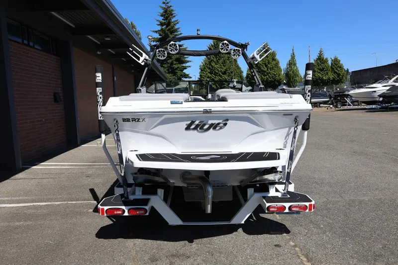 Slide: The Image of 2021 Tigé 22RZX boat rear view in a parking lot, showcasing sleek design and features. - 13