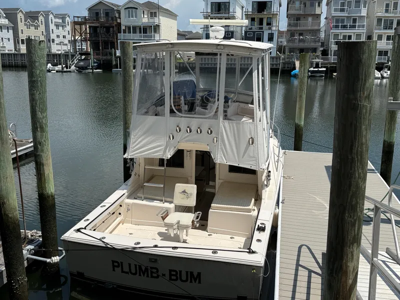 Slide: The Image of 1992 Blackfin 29 Flybridge boat docked in a marina with waterfront homes. - 1