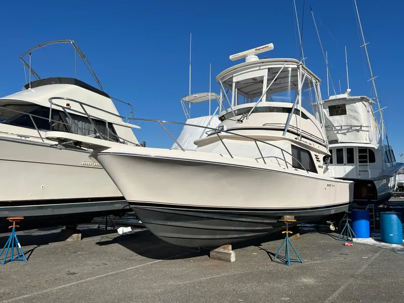Slide: The Image of 1992 Blackfin 29 Flybridge boat on stands, surrounded by other boats, under clear blue sky. - 2