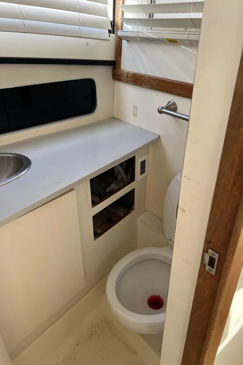Slide: The Image of 1992 Blackfin 29 Flybridge boat bathroom with sink, toilet, and window blinds. - 29