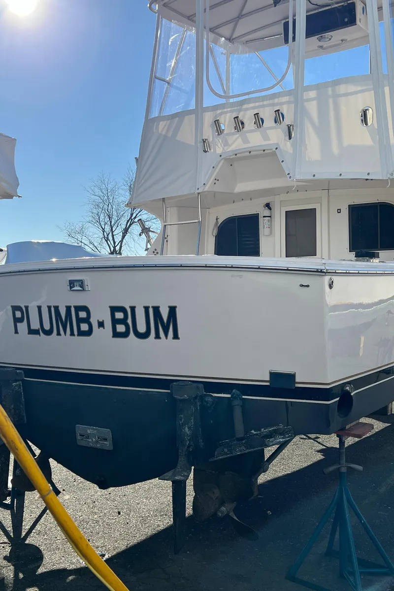 Slide: The Image of 1992 Blackfin 29 Flybridge boat on stands, named "Plumb-Bum," in a sunny outdoor setting. - 5
