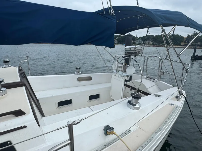 Slide: The Image of 1989 Catalina 34 sailboat with blue canopy docked on calm water. - 1