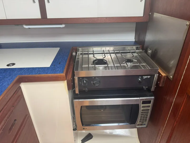 Slide: The Image of Compact kitchen area in a 1989 Catalina 34 sailboat with stove and microwave. - 13