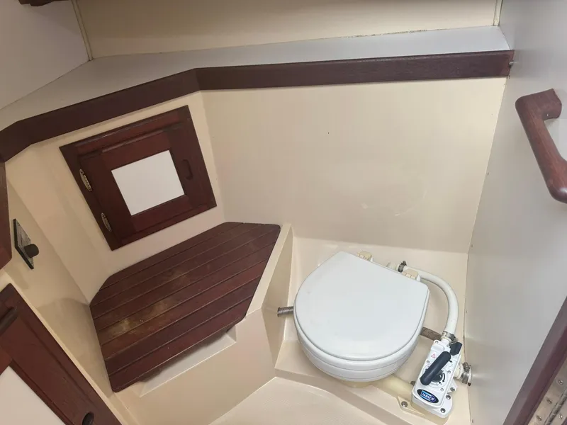 Slide: The Image of 1989 Catalina 34 boat bathroom with wooden accents and marine toilet. - 15
