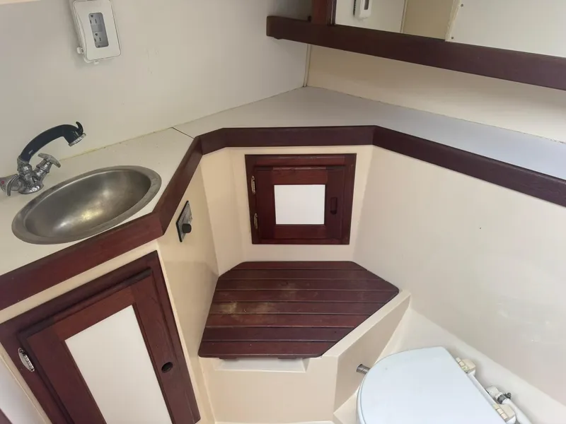 Slide: The Image of 1989 Catalina 34 yacht bathroom with sink, wooden cabinets, and toilet. - 16