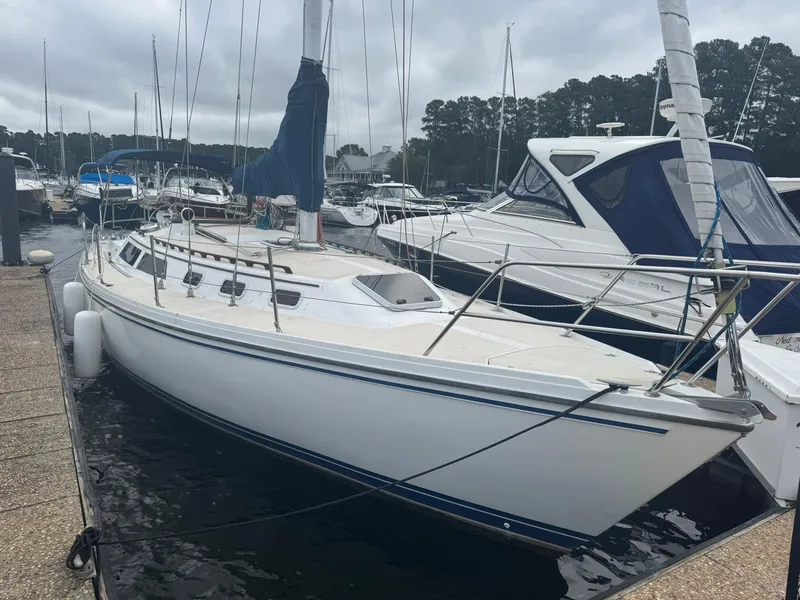 Slide: The Image of 1989 Catalina 34 sailboat docked at a marina on a cloudy day. - 2