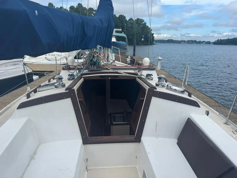 Slide: The Image of 1989 Catalina 34 sailboat docked by a serene lake under a cloudy sky. - 4