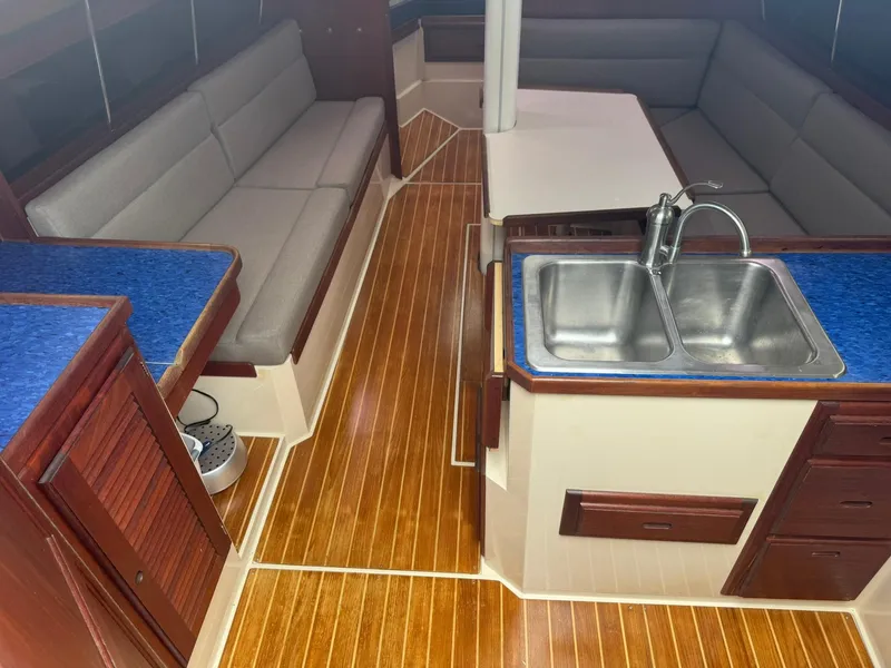 Slide: The Image of Interior of a 1989 Catalina 34 sailboat with wood flooring and a compact kitchen area. - 9