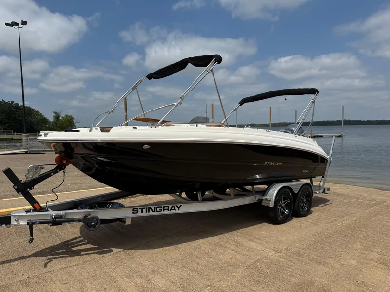 Slide: The Image of 2022 Stingray 212 SC boat on trailer by a lake under a cloudy sky. - 10