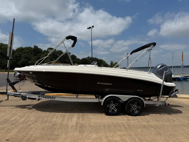 Slide: The Image of 2022 Stingray 212 SC boat on trailer by a lake under a cloudy sky. - 13