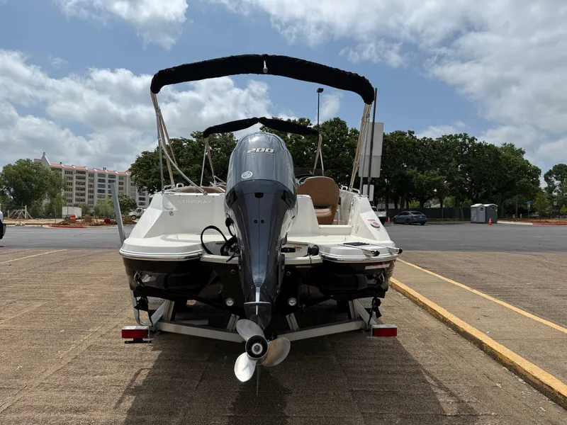 Slide: The Image of 2022 Stingray 212 SC boat on trailer, parked outdoors under cloudy sky. - 21