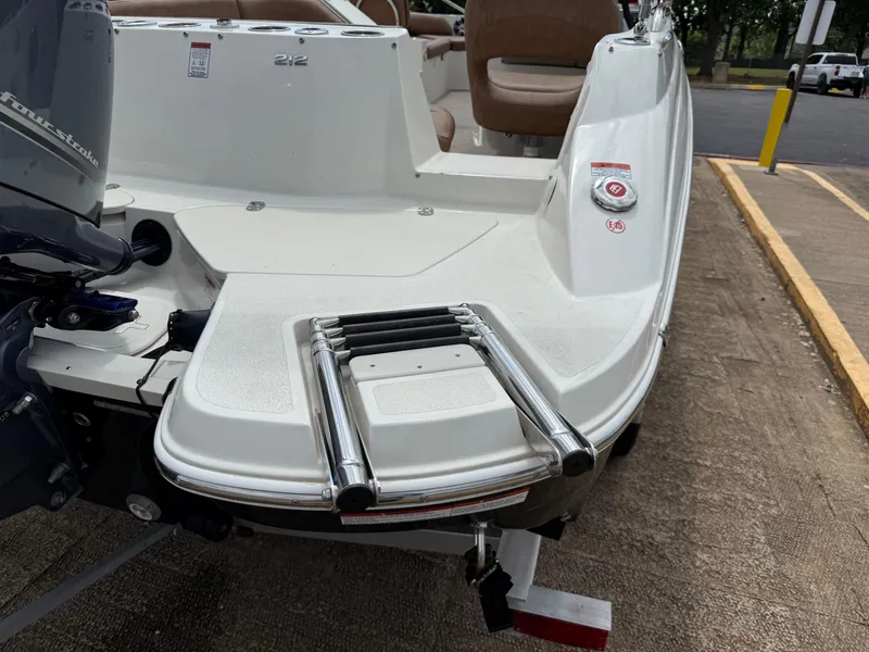 Slide: The Image of 2022 Stingray 212 SC boat with swim platform and ladder, parked on a concrete surface. - 25