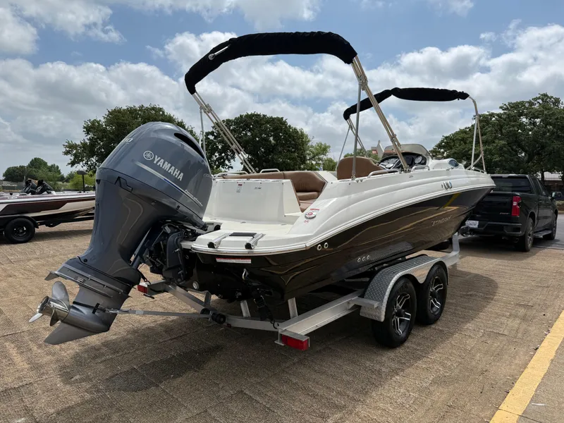 Slide: The Image of 2022 Stingray 212 SC boat on trailer with Yamaha engine, parked outdoors. - 26