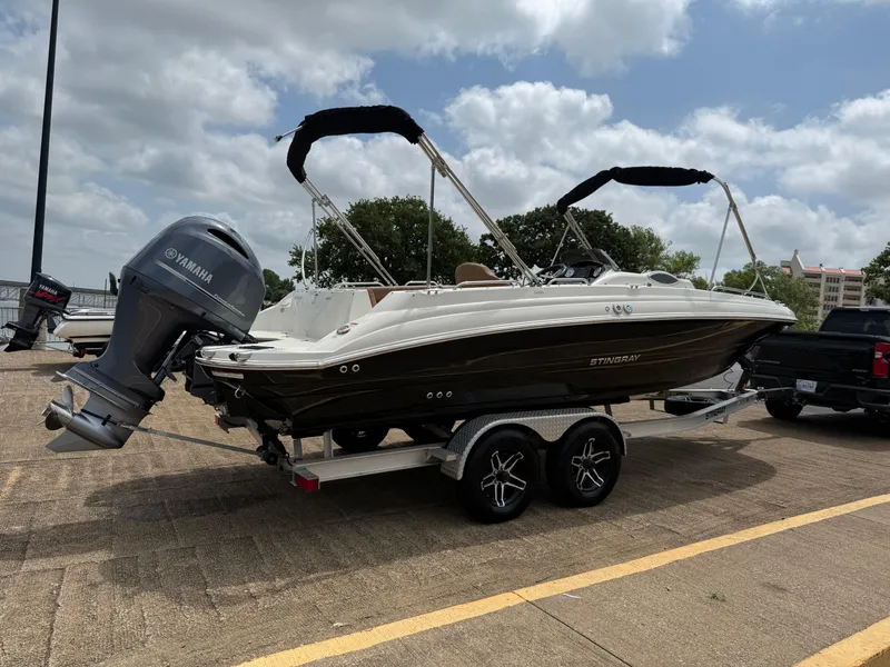 Slide: The Image of 2022 Stingray 212 SC boat on trailer with Yamaha outboard motor, parked outdoors. - 27