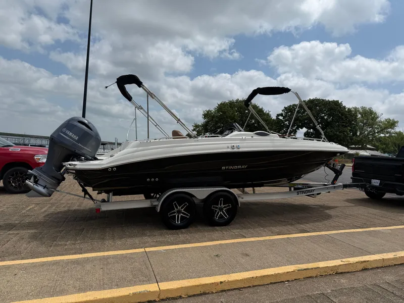 Slide: The Image of 2022 Stingray 212 SC boat on trailer, parked outdoors under cloudy sky. - 29