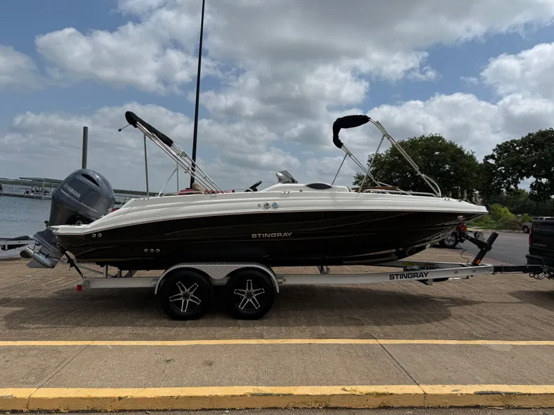 Slide: The Image of 2022 Stingray 212 SC boat on trailer by waterfront, under cloudy sky. - 30