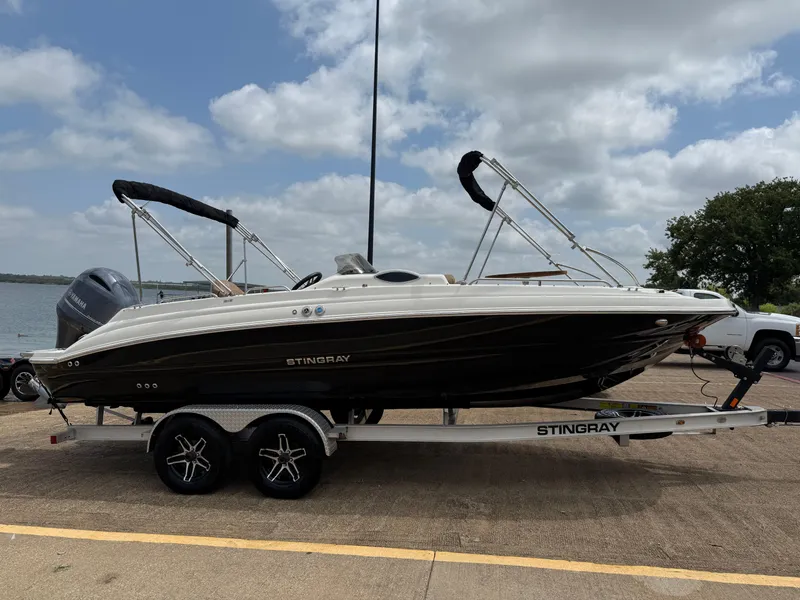 Slide: The Image of 2022 Stingray 212 SC boat on trailer, parked near a lake under a cloudy sky. - 31