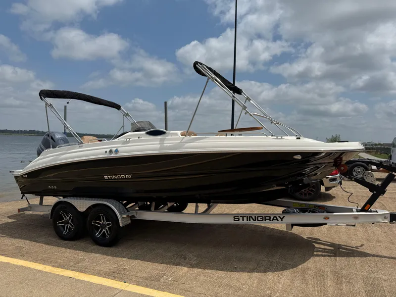 Slide: The Image of 2022 Stingray 212 SC boat on trailer by a lake under cloudy sky. - 32